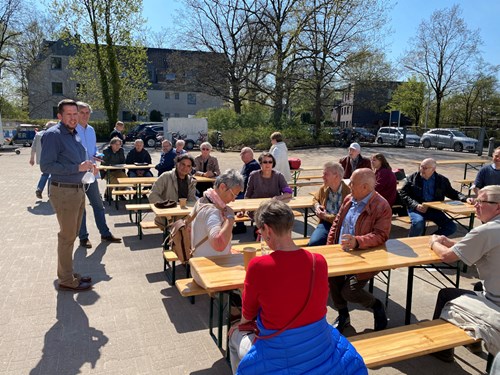 Mitgliedervertretende sitzen auf Bierbänken im Freien